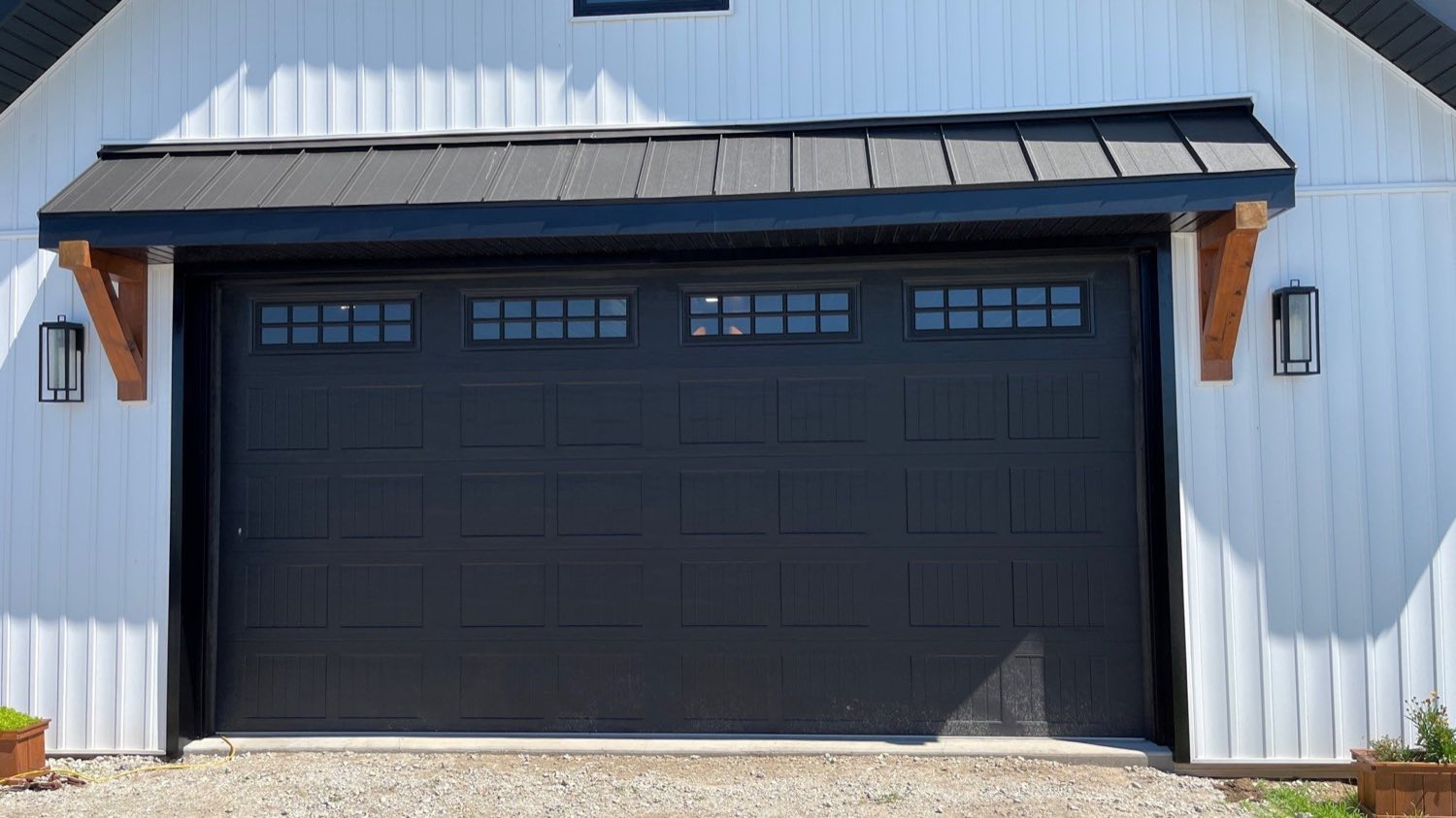 New garage built onto a farmhouse, black carriage doors under a standing-seam roof