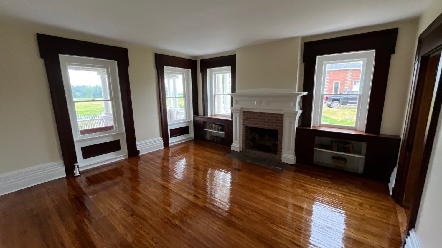 Restored parlor with original dark trim, a tall fireplace mantel, and refinished hardwood floors