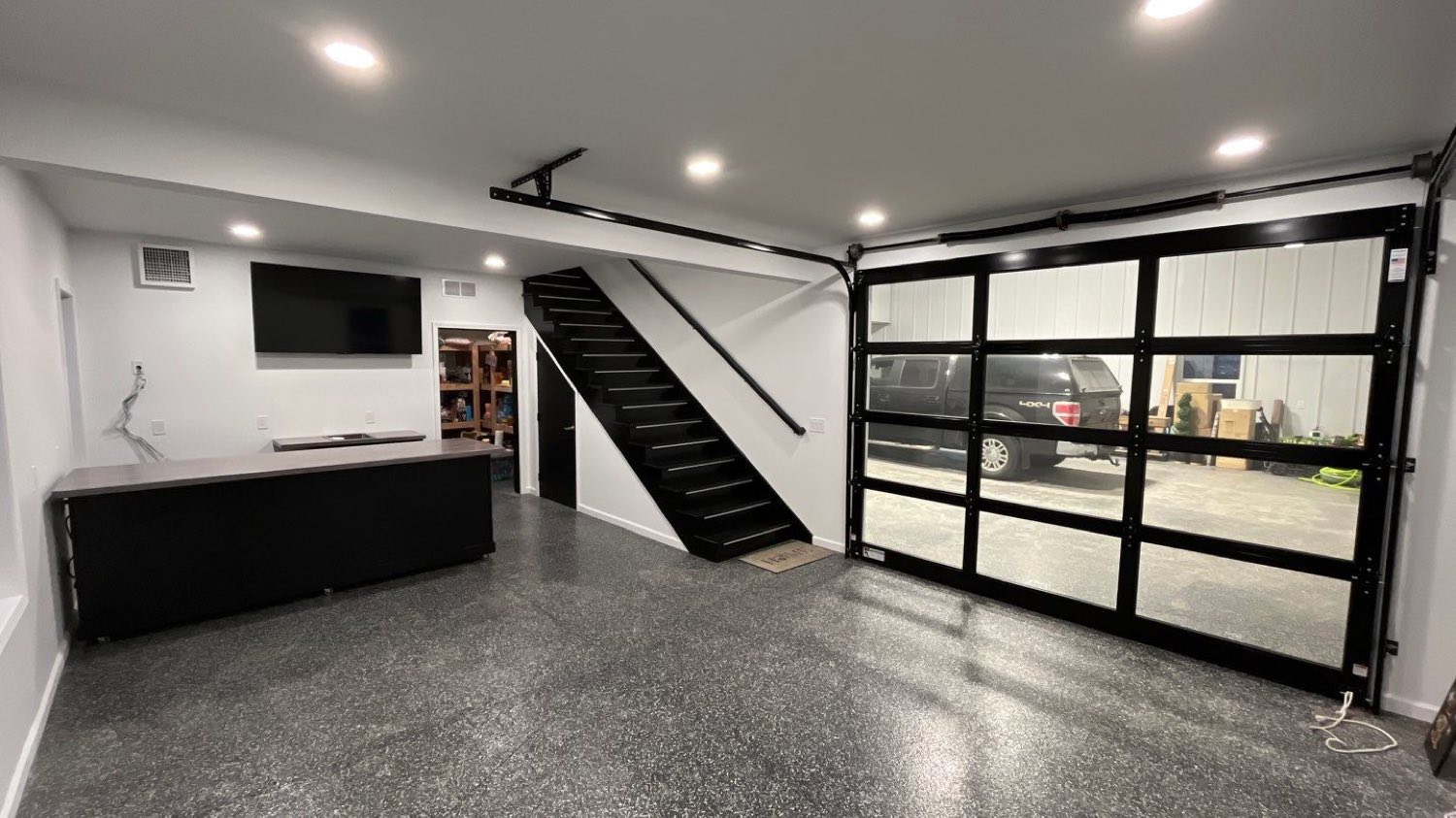 Finished barndominium great room with an open steel stair and glass overhead doors